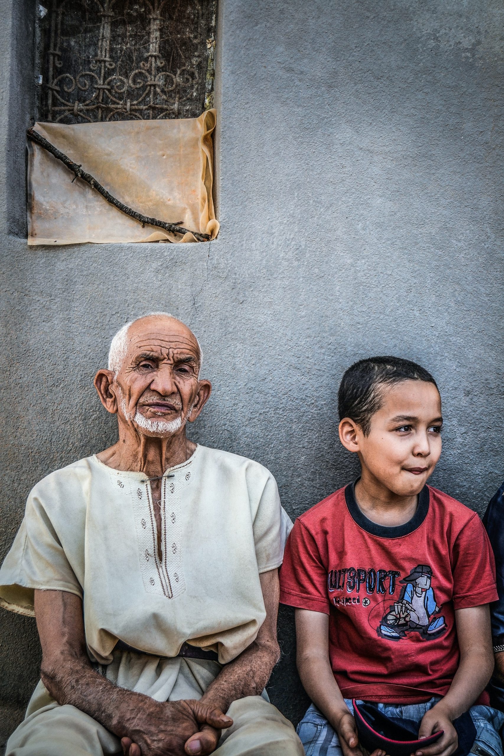 An old man and a boy sitting together in a hot country. Photo by Nourdine Diouane on Unsplash